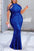 Blue lace dress with cut-out shoulders on a woman standing on a sidewalk.