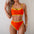 Woman wearing a bright orange bikini with yellow accents against a plain background