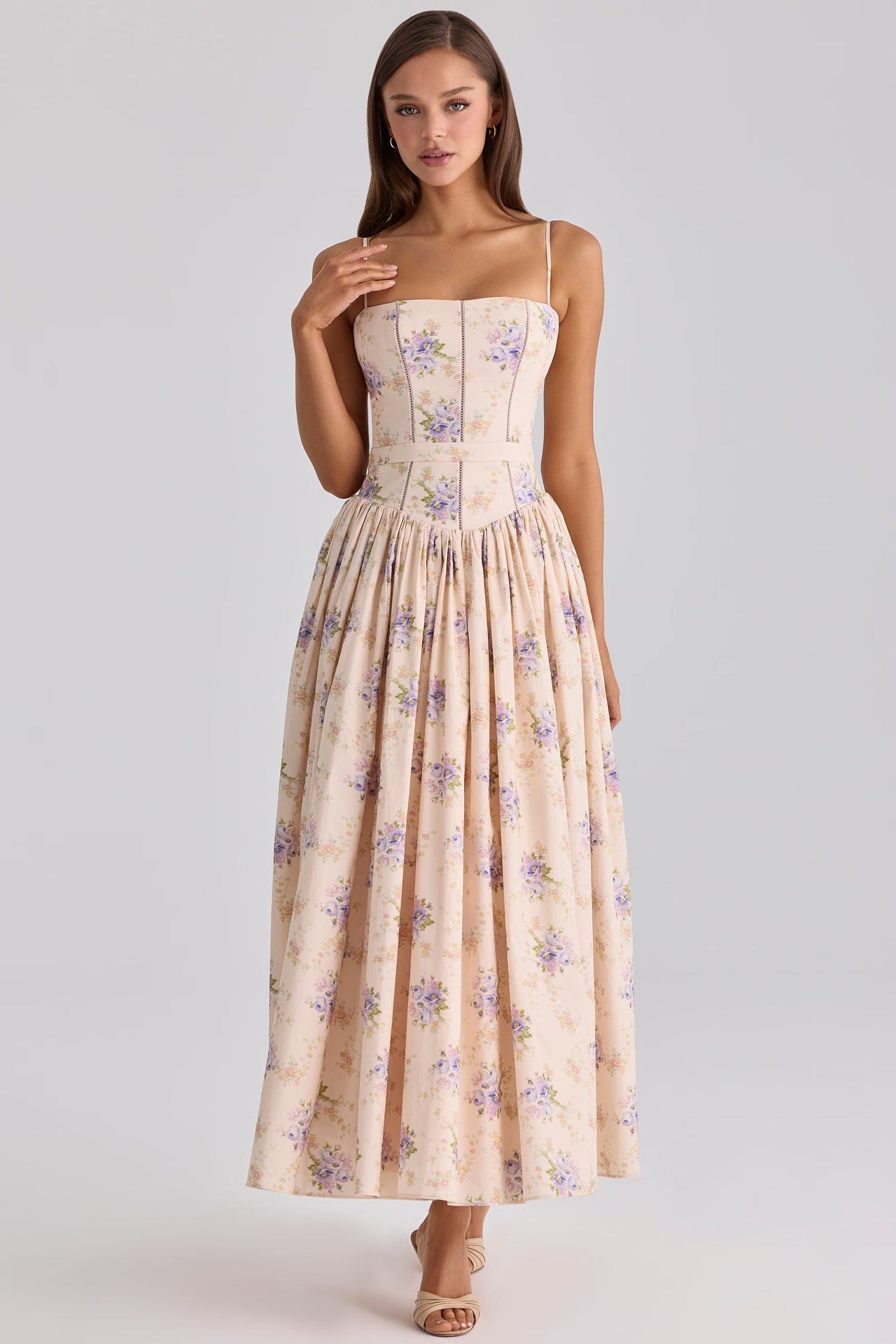 Woman wearing a floral strapless dress on a plain background