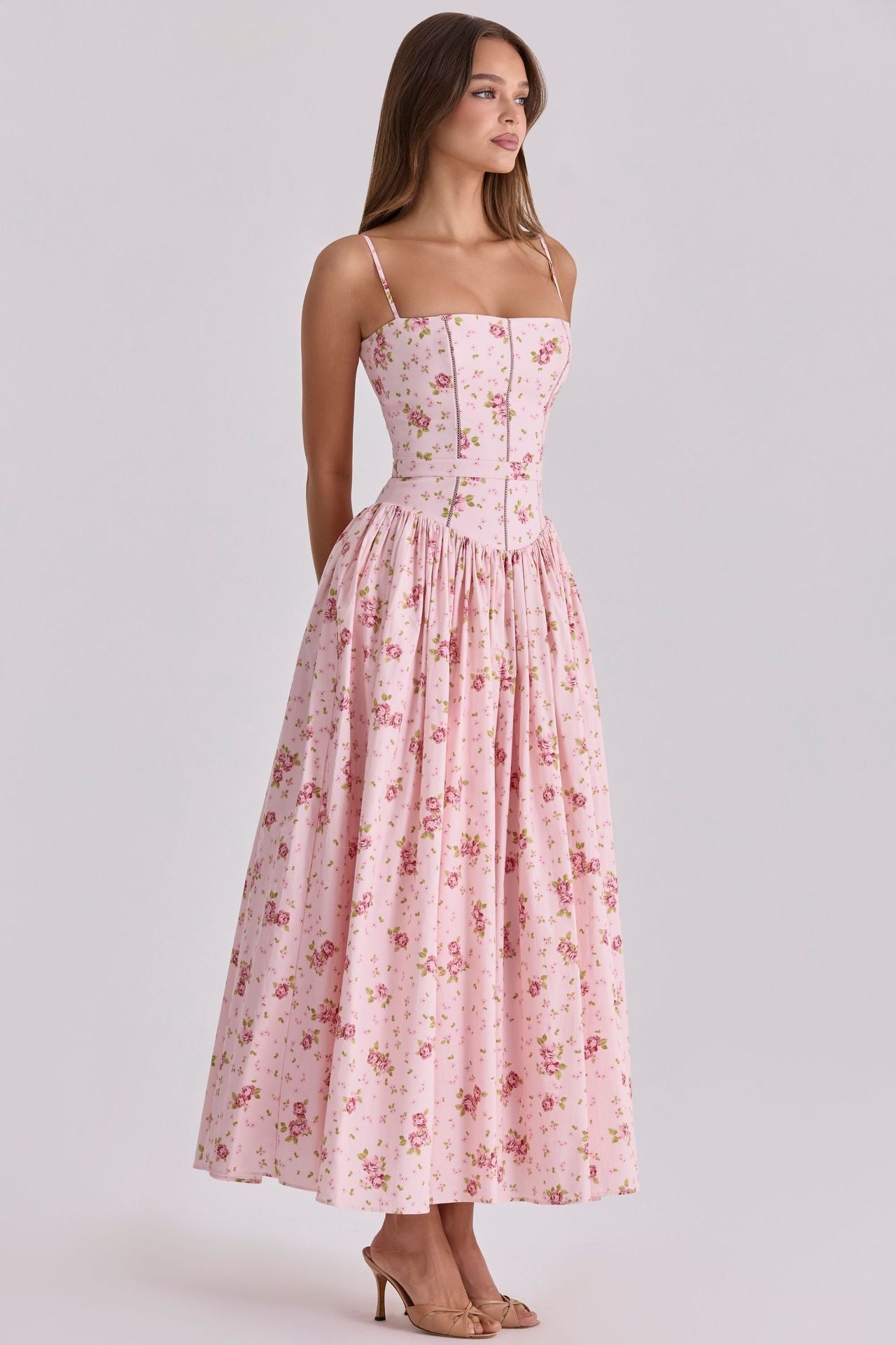 Woman wearing a pink floral dress on a light gray background