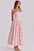 Woman wearing a pink floral dress on a light gray background