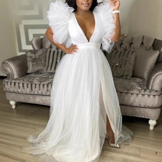 Woman wearing a white dress with ruffled sleeves in a living room setting.