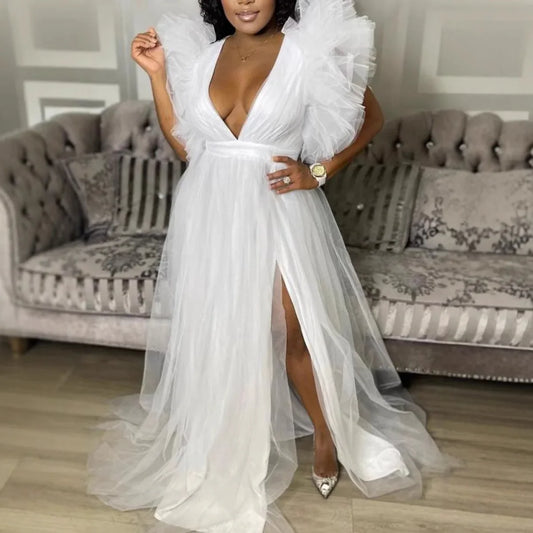 Woman wearing a white dress with ruffled sleeves in a living room setting.