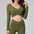 Woman wearing an olive green long-sleeve top and leggings set on a gray background
