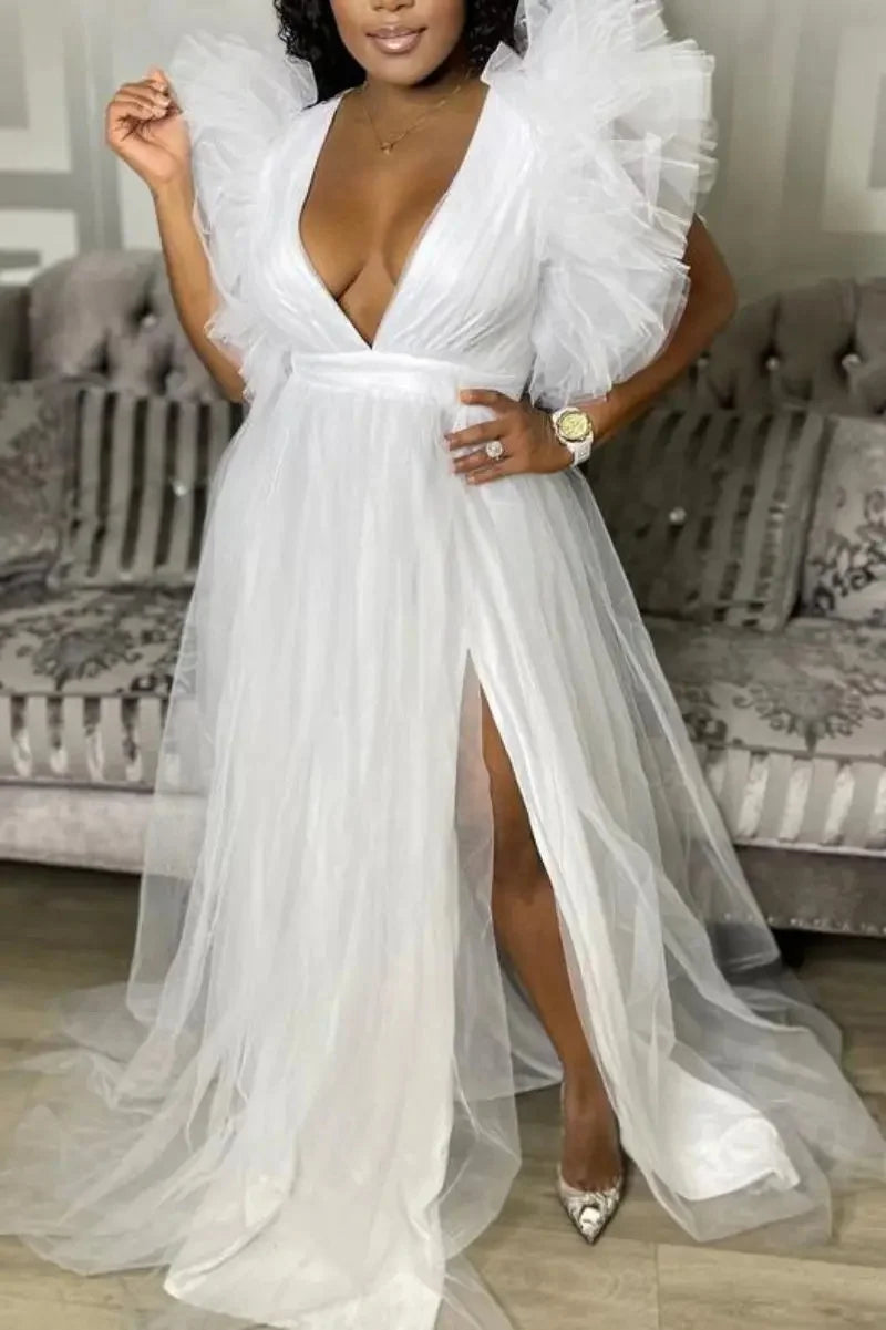 Woman wearing a white dress with ruffled sleeves in a living room setting.