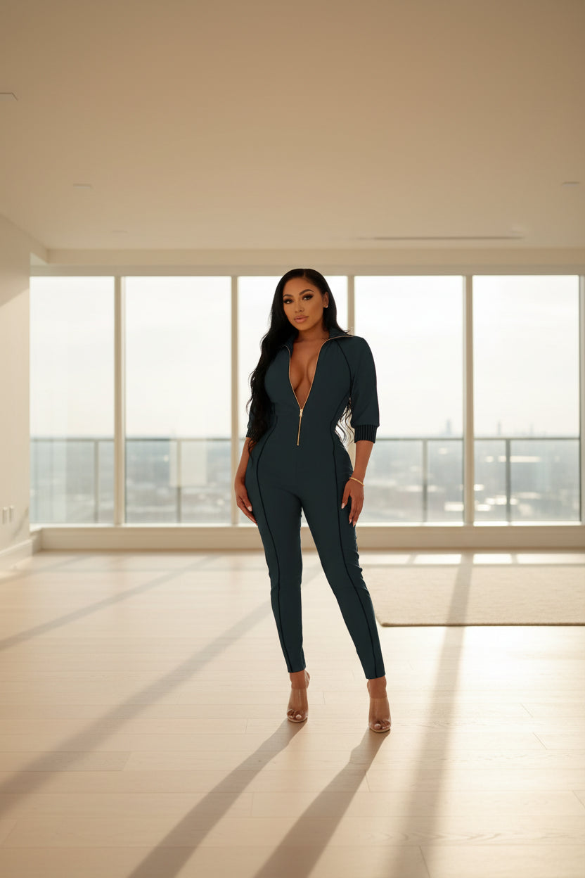 Woman wearing a dark green jumpsuit with a deep neckline in an indoor setting.