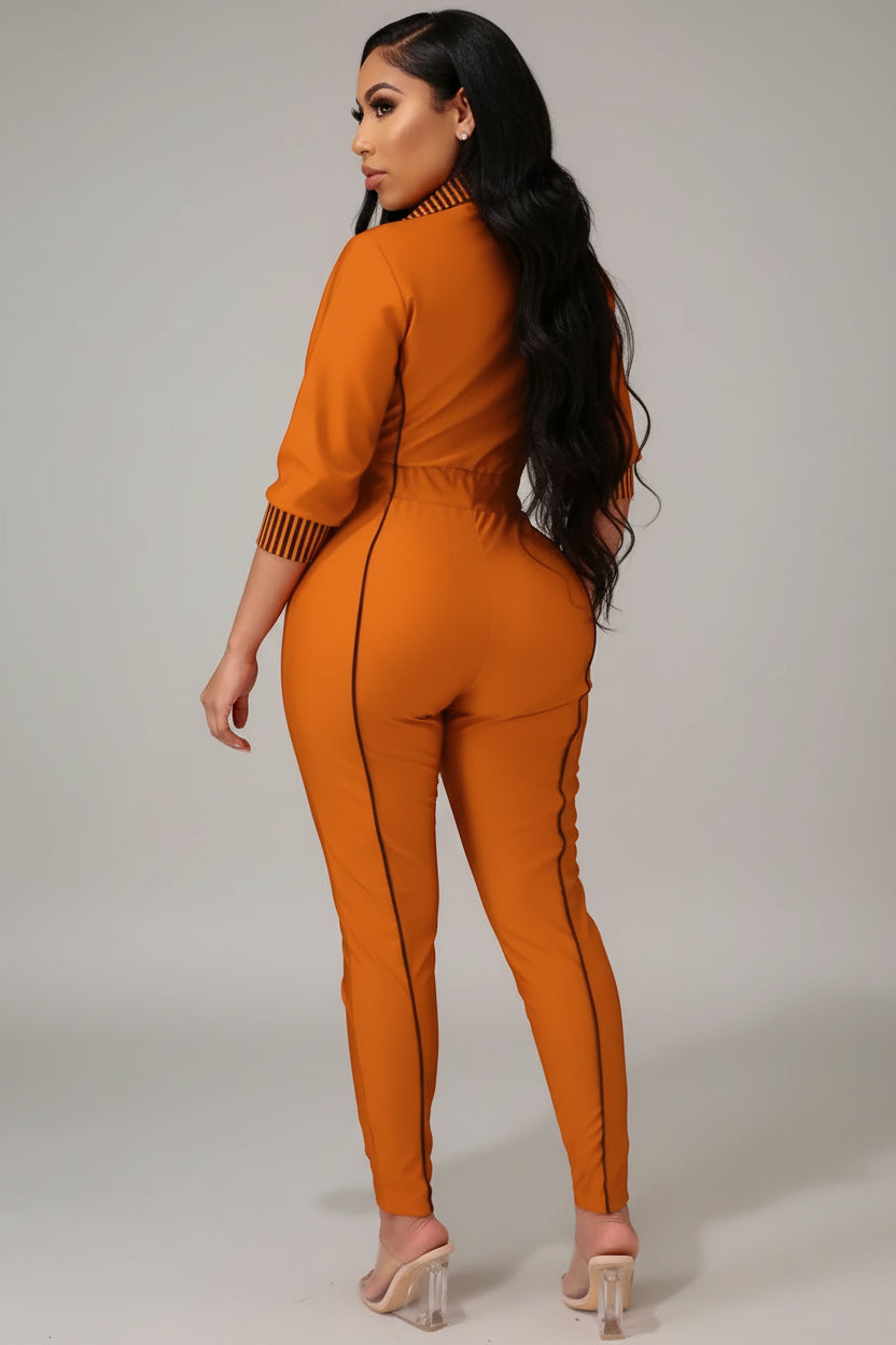 A woman wearing an orange jumpsuit is standing in a room with a mirror on the wall.