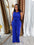 Woman in a blue jumpsuit standing in front of a mirror with curtains in the background