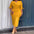 A woman wearing a yellow dress is standing in front of a glass door.
